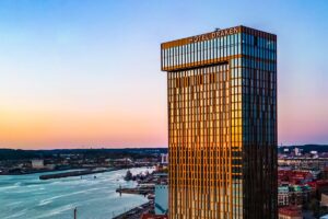 Clarion Hotel Draken i Göteborg – det 34 våningar höga glastornet med Hotel Draken-skylten i solnedgång, med Göta älv i bakgrunden