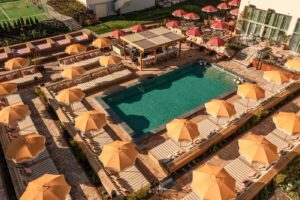 Utomhuspool med solsängar och orange parasoll vid Pool Club på Hjortviken Country Club i Hindås