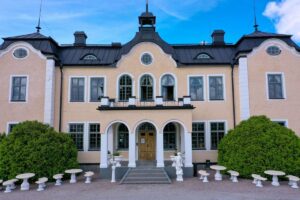 Johannesbergs Slott i Gottröra – den ljusa slottsfasaden med entrétrappa och trädgårdsmöbler