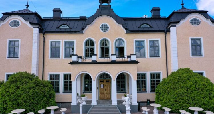 Johannesbergs Slott i Gottröra – den ljusa slottsfasaden med entrétrappa och trädgårdsmöbler